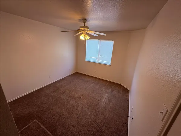 an empty room with a chandelier fan and windows