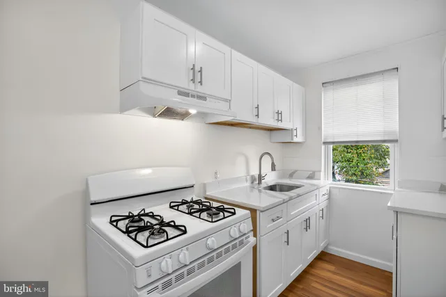a kitchen with white cabinets stove and sink