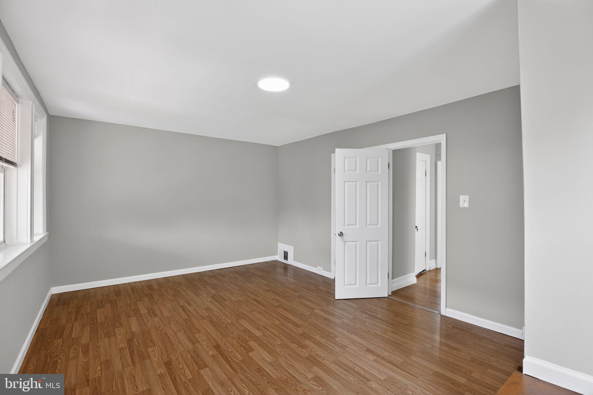 5446 Narcissus Avenue, Unit 2 Baltimore, MD 21215 - Photo 6 of 18 an empty room with wooden floor and windows