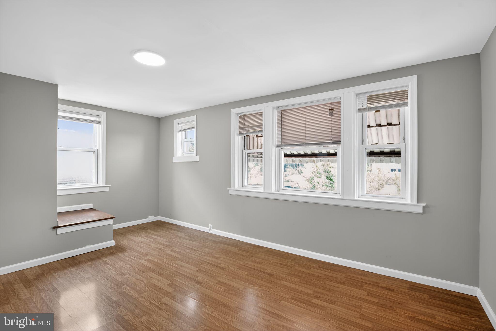 5446 Narcissus Avenue, Unit 2 Baltimore, MD 21215 - Photo 7 of 18 a view of an empty room with wooden floor and a window