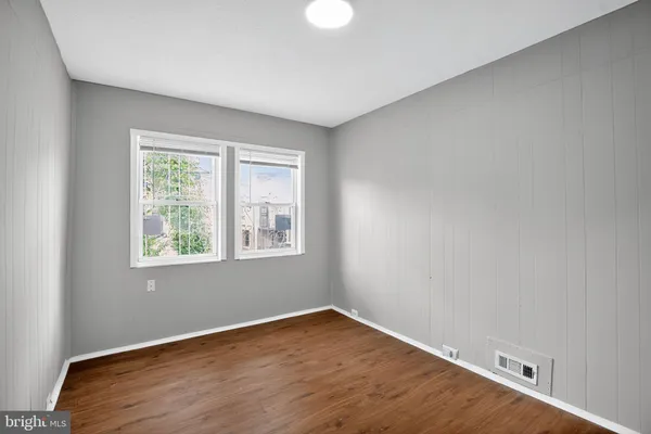 an empty room with wooden floor and windows
