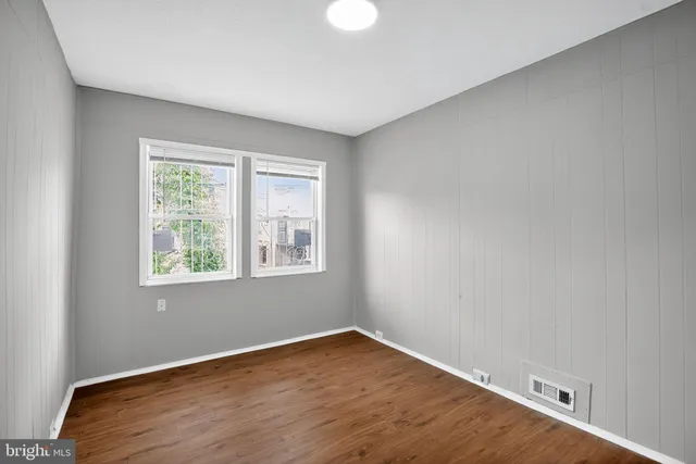 an empty room with wooden floor and windows