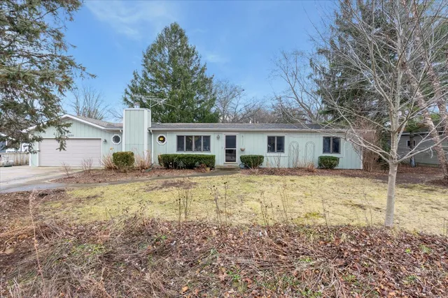 a front view of a house with a yard covered with trees