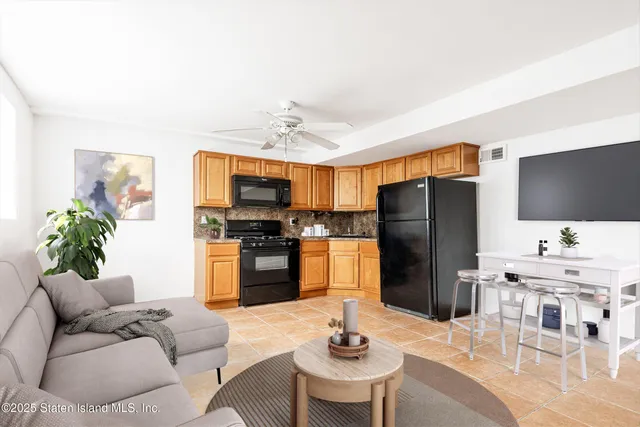 a living room with stainless steel appliances kitchen island granite countertop furniture and a flat screen tv