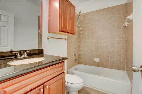 a bathroom with a granite countertop sink a toilet and bathtub