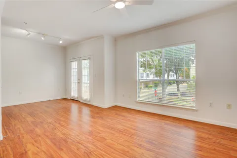 a view of an empty room with wooden floor and a window