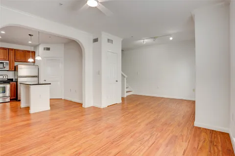 a view of empty room with wooden floor and kitchen