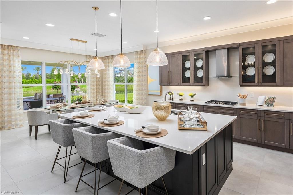 12100 Eucalyptus Way Naples, FL 34120 - Photo 2 of 36 a kitchen with a stove a sink a kitchen island with chairs and wooden cabinets