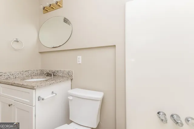 a bathroom with a granite countertop toilet sink and mirror