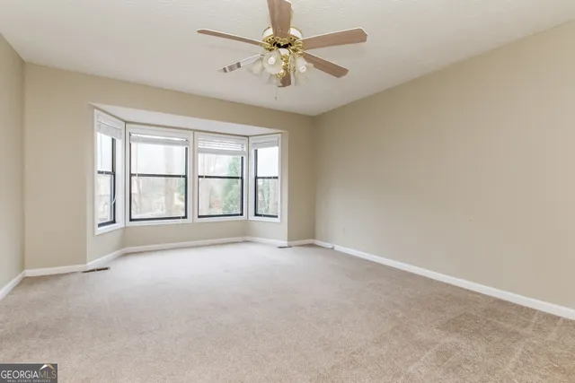 an empty room with windows and ceiling fan