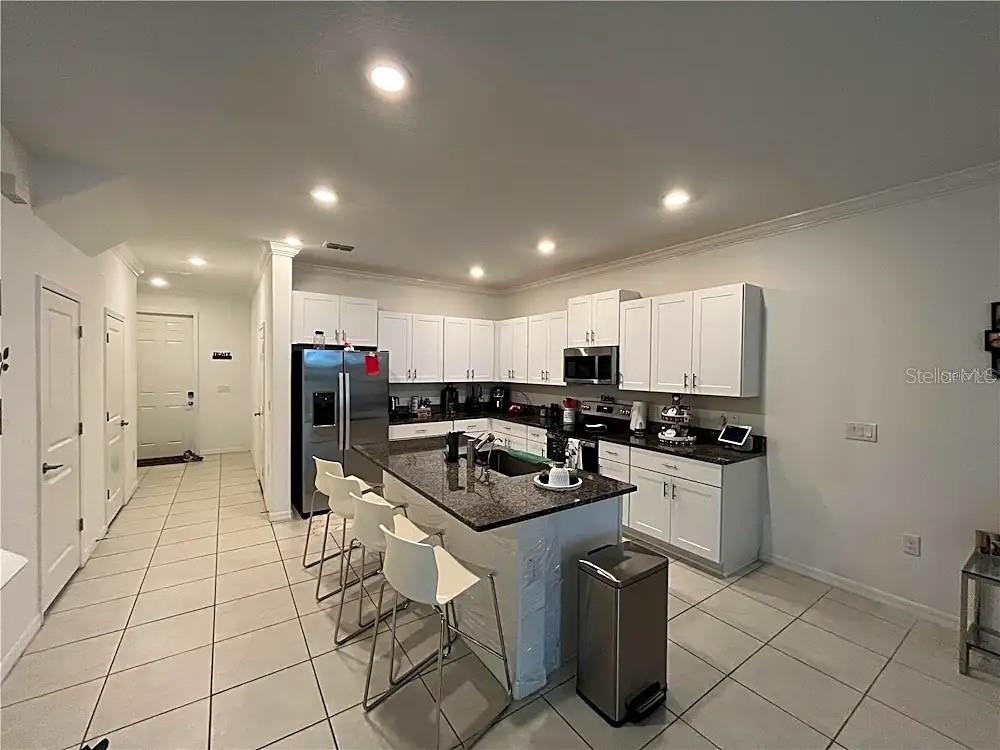 31751 Blue Passing Loop Wesley Chapel, FL 33545 - Photo 4 of 18 a kitchen with stainless steel appliances granite countertop a sink a stove a refrigerator a counter top space and cabinets