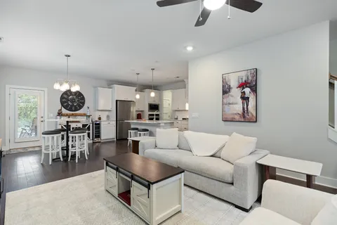 a living room with furniture kitchen view and a chandelier