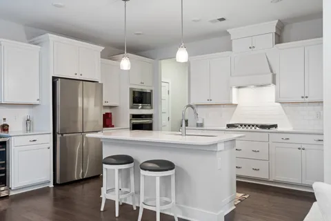 a kitchen with stainless steel appliances a stove a refrigerator and white cabinets with wooden floors