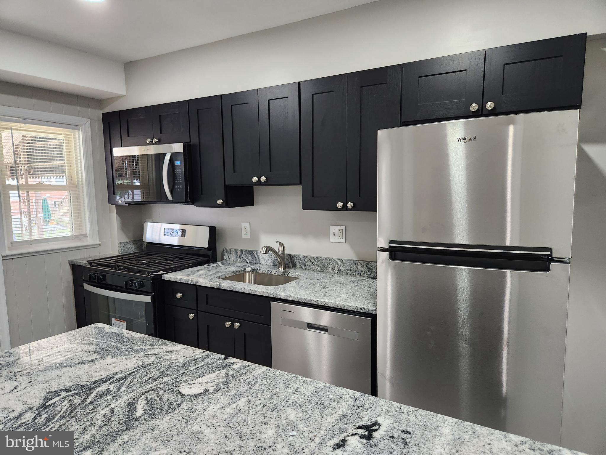 4113 Century Road Baltimore, MD 21206 - Photo 7 of 27 a kitchen with granite countertop a refrigerator and a stove top oven