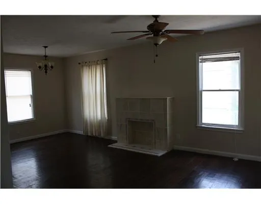 a living room with a fireplace furniture a ceiling fan and a window