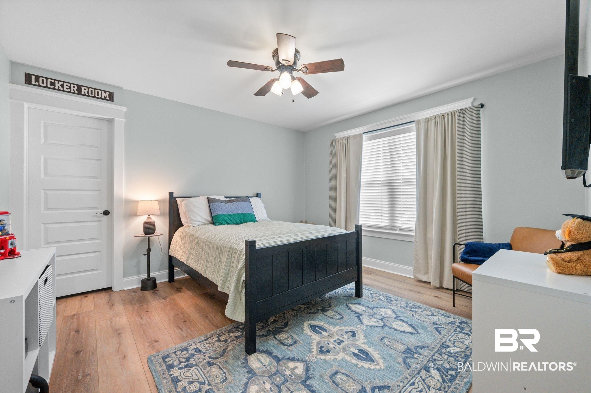 409 Fortune Drive Fairhope, AL 36532 - Photo 23 of 42 Bedroom featuring wood-finish flooring, a ceiling fan with light, a white paneled door, a window with blinds and curtains, and light-colored wall paint