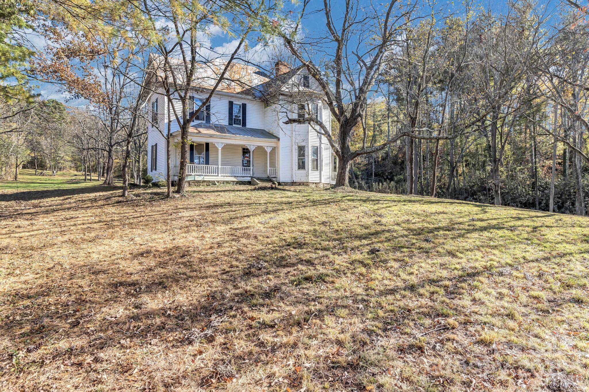 143 Sharon Road Fairview, NC 28730 - Photo 5 of 36 a yellow house with trees in front of it