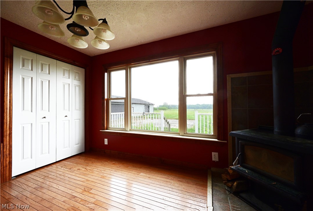 19105 Whitehead Road Lagrange, OH 44050 - Photo 22 of 37 Bedroom with a closet, hardwood / wood-style flooring, a chandelier, a wood stove, and a textured ceiling