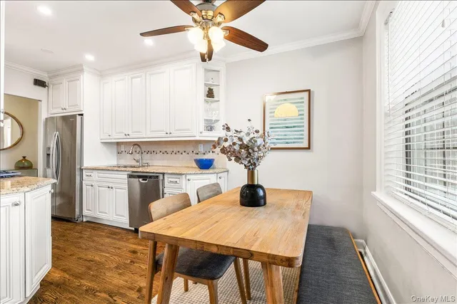 a kitchen with stainless steel appliances kitchen island granite countertop a sink a stove a refrigerator with a dining table and chairs