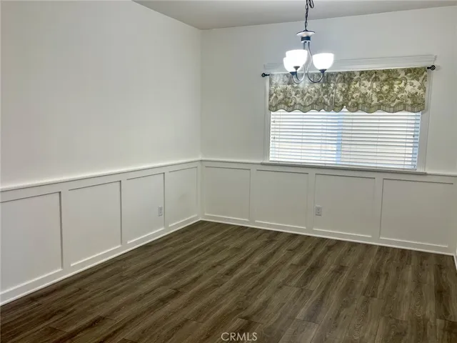 an empty room with wooden floor chandelier and windows