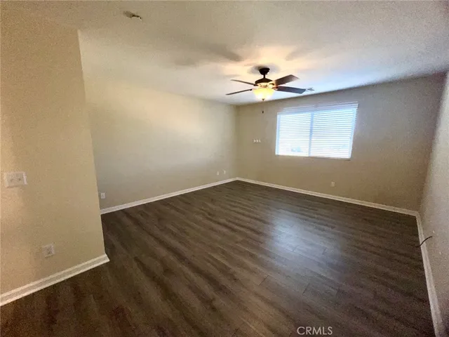 an empty room with wooden floor chandelier fan and windows