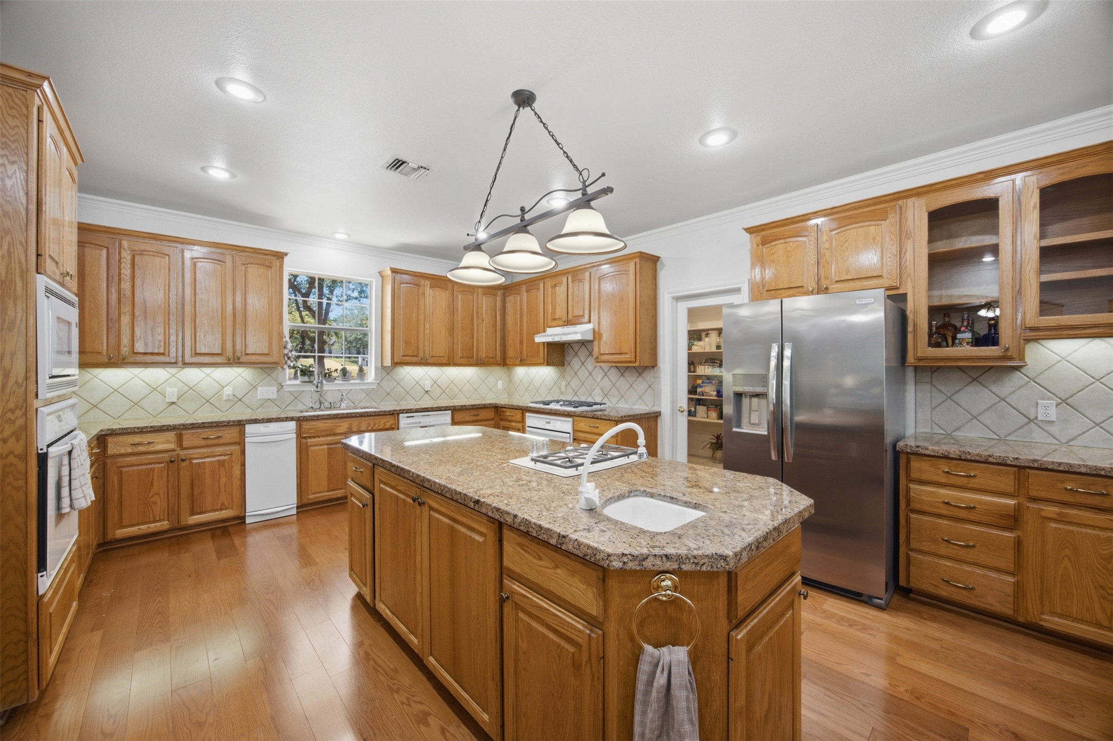 197 Elm Wood Drive Elgin, TX 78621 - Photo 7 of 37 A spacious culinary haven with rich wooden cabinetry, gleaming countertops, and an inviting central island.