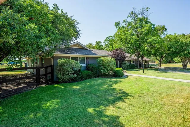 a view of a house next to a big yard and large trees