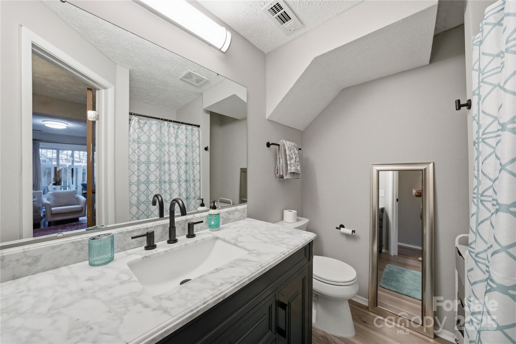 1235 Scaleybark Road, Unit C Charlotte, NC 28209 - Photo 24 of 33 a bathroom with a granite countertop sink a toilet a mirror and shower