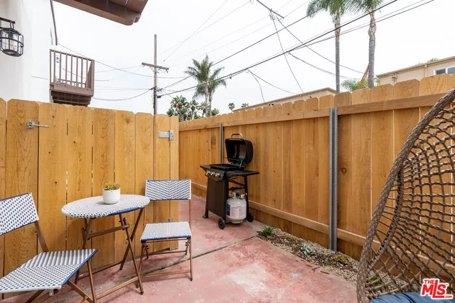 a patio with table and chairs and potted plants