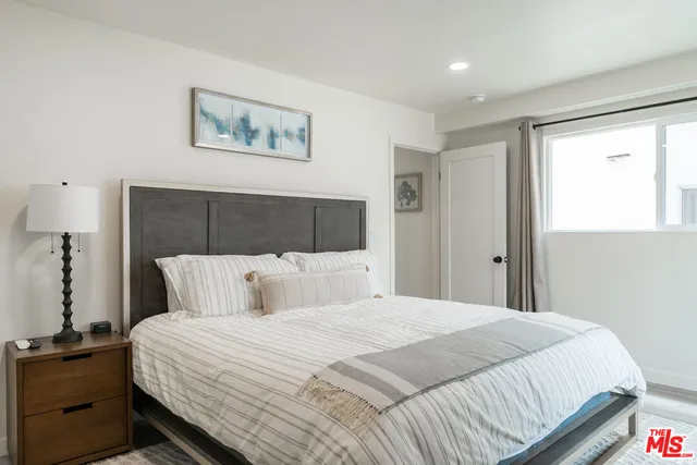 a bedroom with a large bed and a lamp on dresser