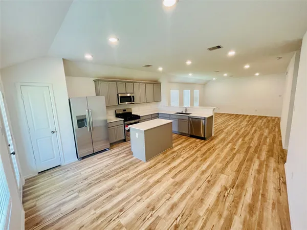 a large kitchen with a sink and dishwasher a refrigerator with wooden floor