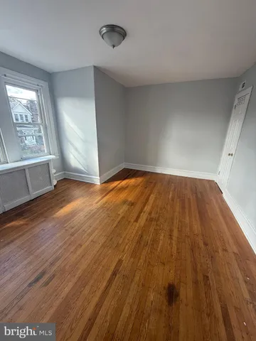 an empty room with wooden floor chandelier fan and windows