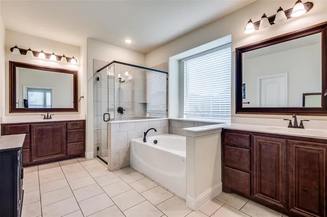 a bathroom with a tub a sink double vanity and a mirror