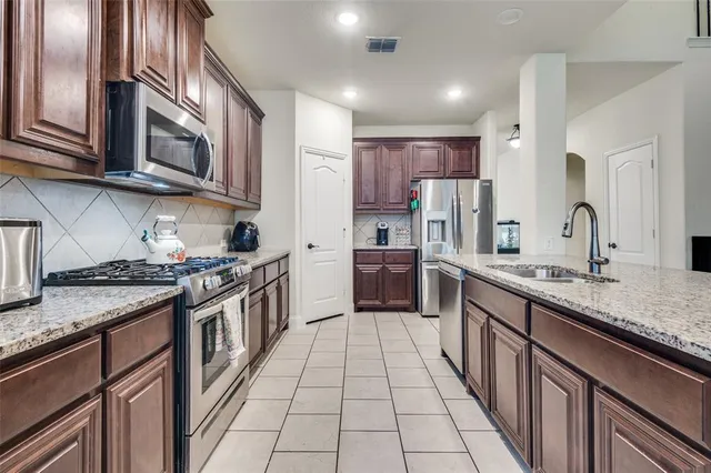a kitchen with stainless steel appliances granite countertop a stove top oven a sink and dishwasher