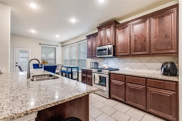 a kitchen with stainless steel appliances granite countertop wooden cabinets a stove top oven a sink and dishwasher