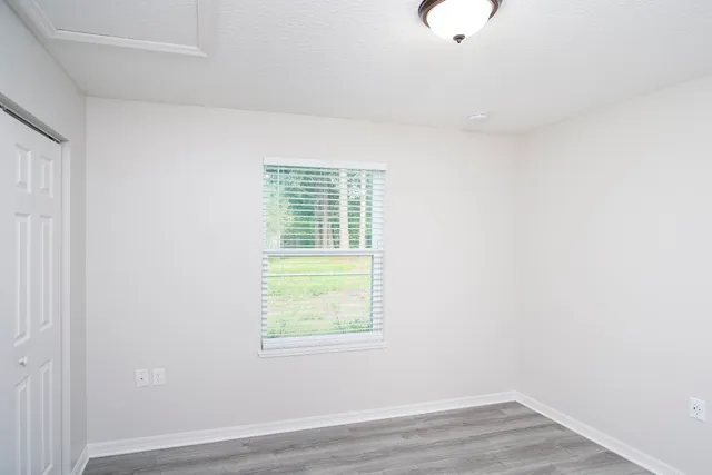a view of an empty room with wooden floor and a window
