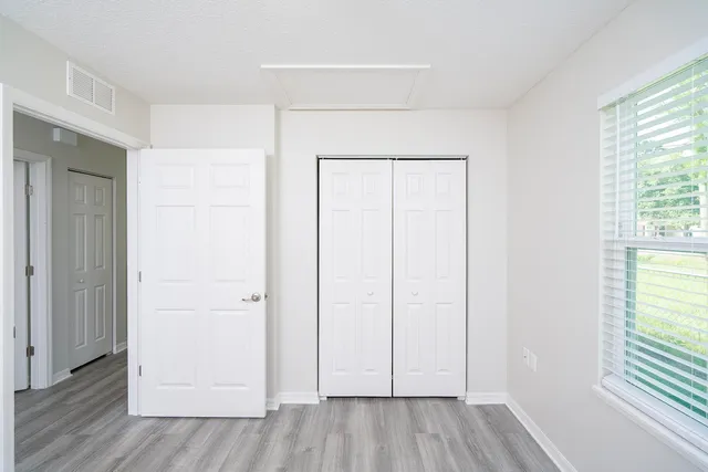 an empty room with wooden floor and windows