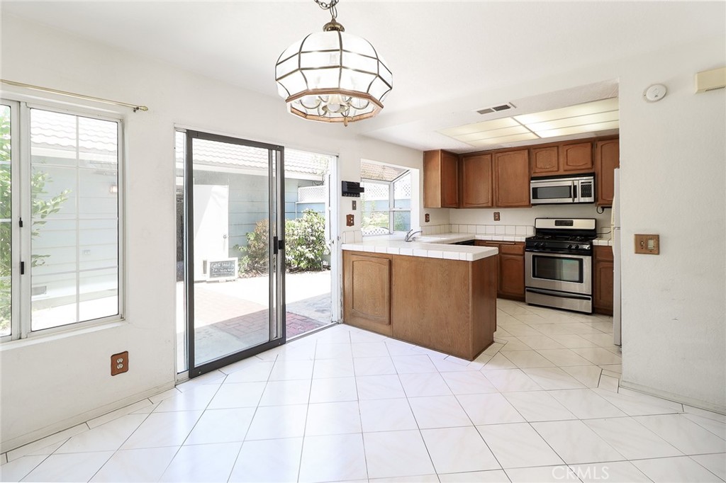345 Jeremiah Drive, Unit C Simi Valley, CA 93065 - Photo 5 of 66 a large kitchen with stainless steel appliances granite countertop a stove top oven a sink dishwasher and a refrigerator with wooden floor