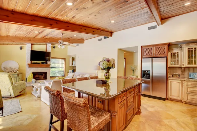 a kitchen with stainless steel appliances kitchen island granite countertop a table chairs in it and a flat screen tv