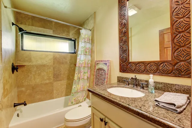 a bathroom with a granite countertop sink toilet tub and shower