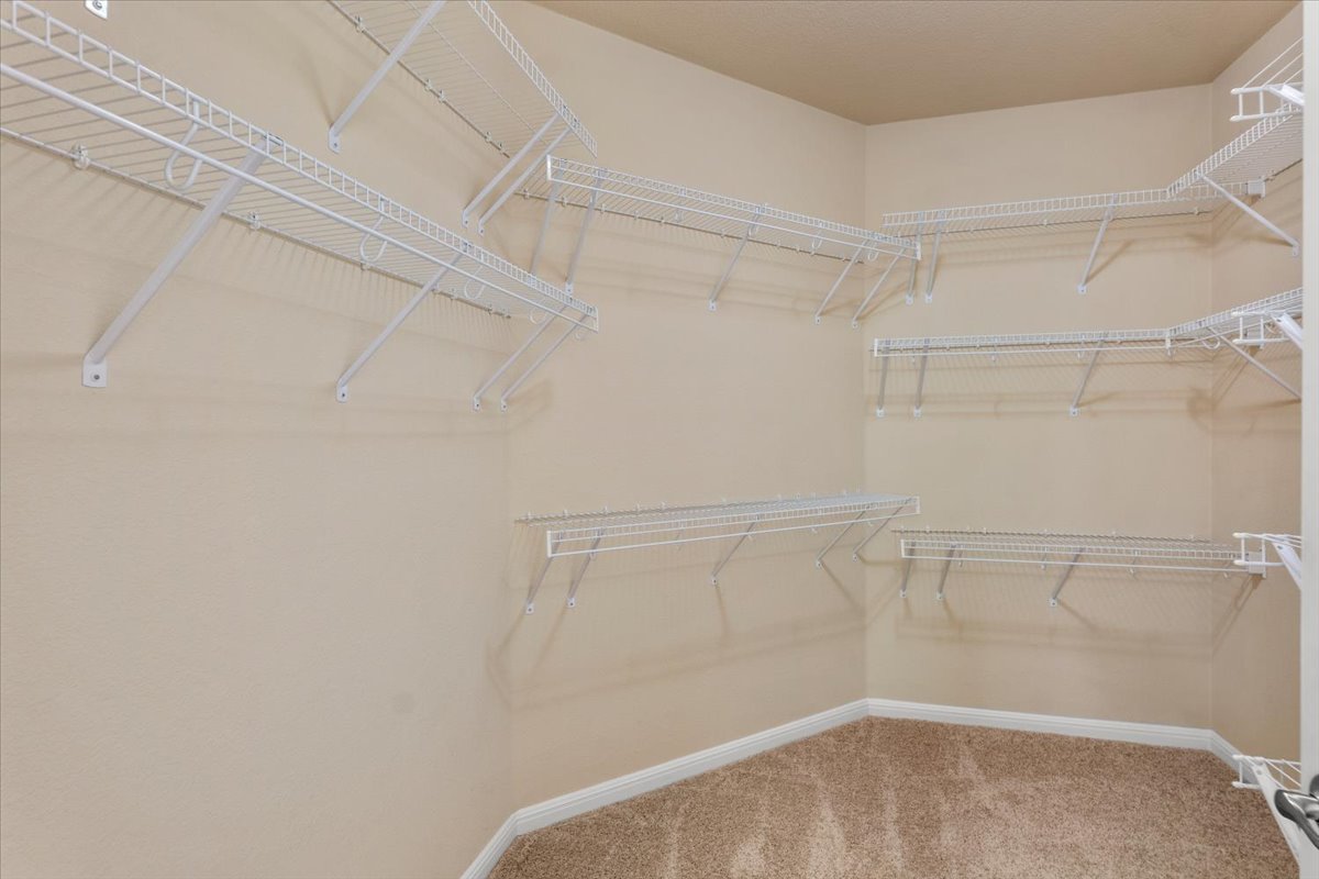 3451 Mayfield Ranch Boulevard, Unit 311 Round Rock, TX 78681 - Photo 35 of 40 Closet featuring a tiered wire shelving system, corner shelving, wall-to-wall carpeting, and neutral wall tones