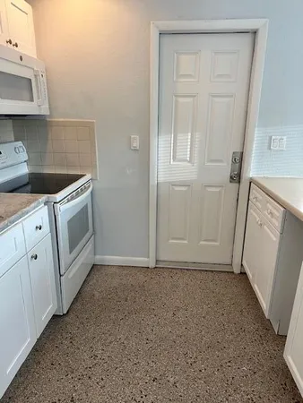 a view of a kitchen with white cabinets and white appliances