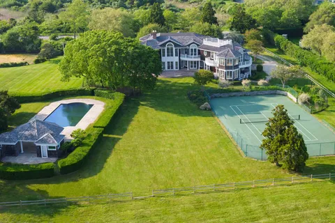 an aerial view of a house with swimming pool and large trees