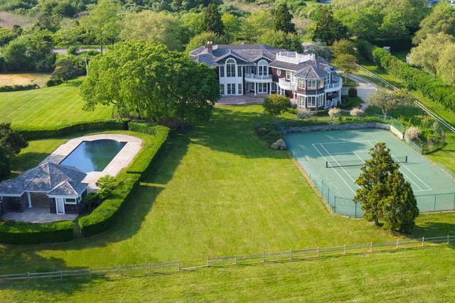 an aerial view of a house with swimming pool and large trees