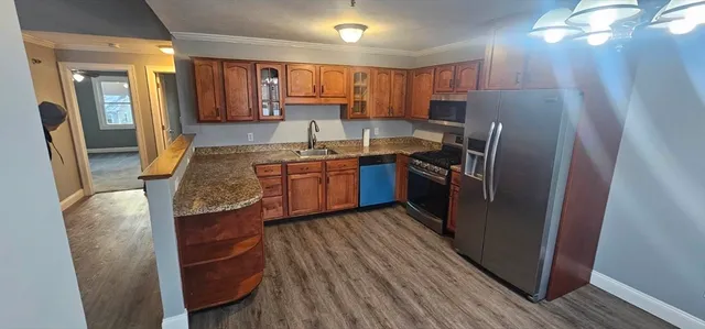 a kitchen with stainless steel appliances granite countertop wooden cabinets a refrigerator a sink a stove a washer dryer and a refrigerator