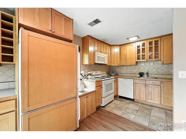 a kitchen with granite countertop a refrigerator a sink and white cabinets