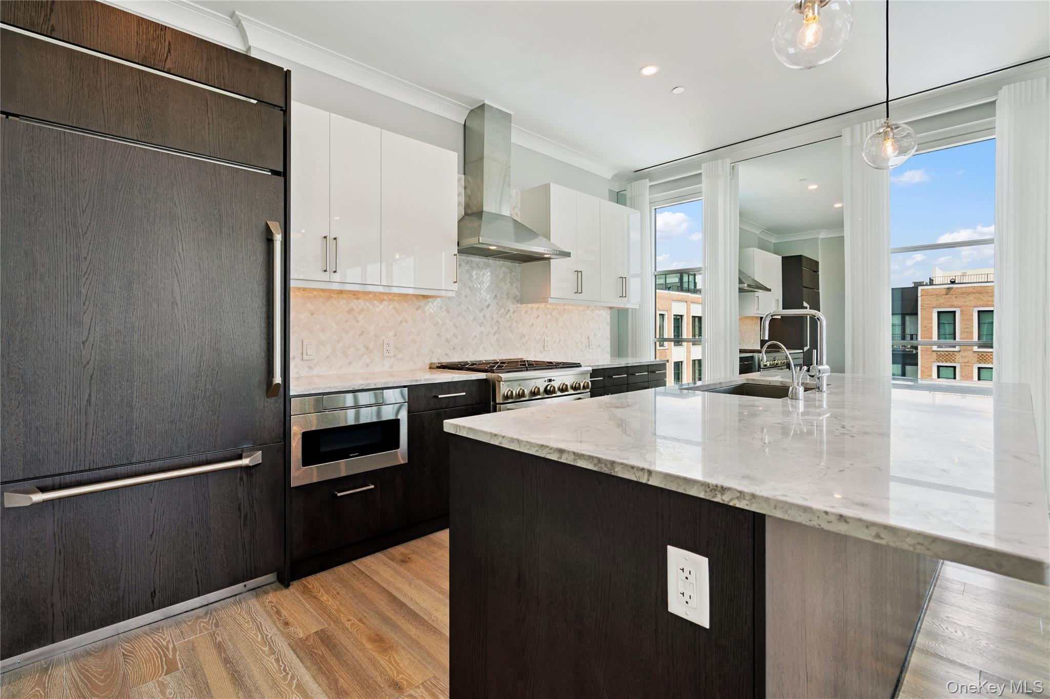 100 Garvies Point Road, Unit 1304 Glen Cove, NY 11542 - Photo 10 of 34 Kitchen white cabinetry, decorative backsplash, wall chimney range hood, and stainless steel microwave