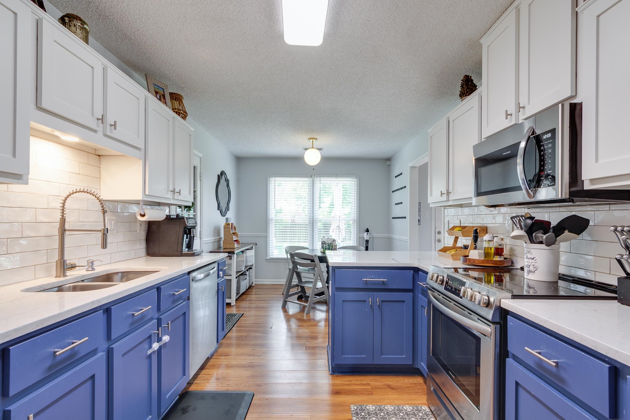 8703 Old River Road Memphis, TN 38018 - Photo 13 of 31 Kitchen with appliances with stainless steel finishes, blue cabinets, light countertops, white cabinetry, and a textured ceiling