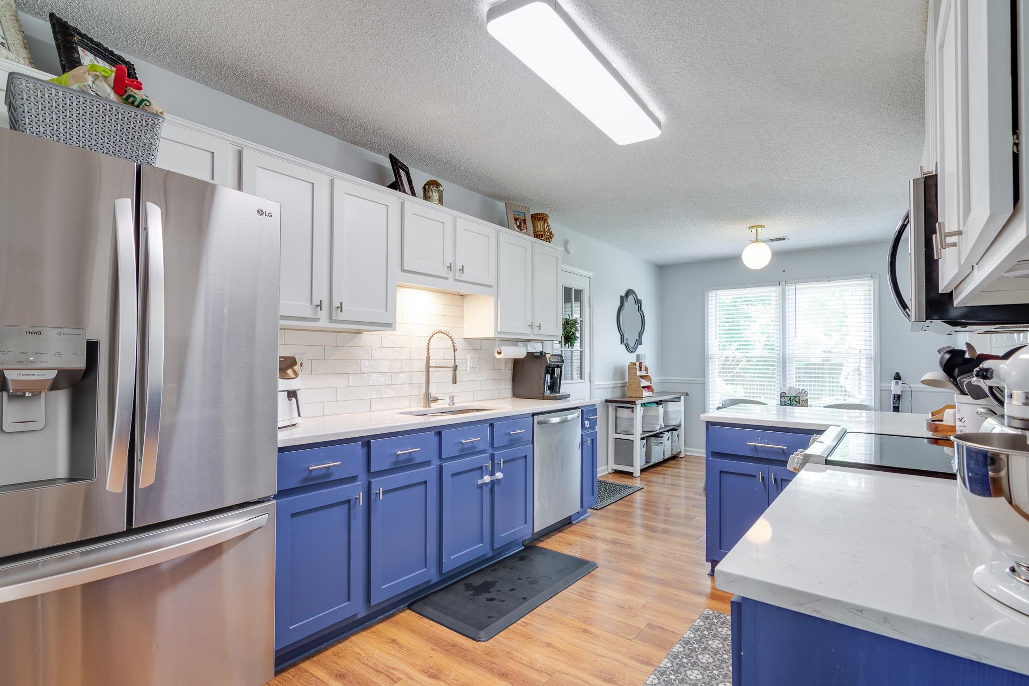 8703 Old River Road Memphis, TN 38018 - Photo 14 of 31 Kitchen with appliances with stainless steel finishes, blue cabinetry, white cabinets, light wood-style floors, and tasteful backsplash