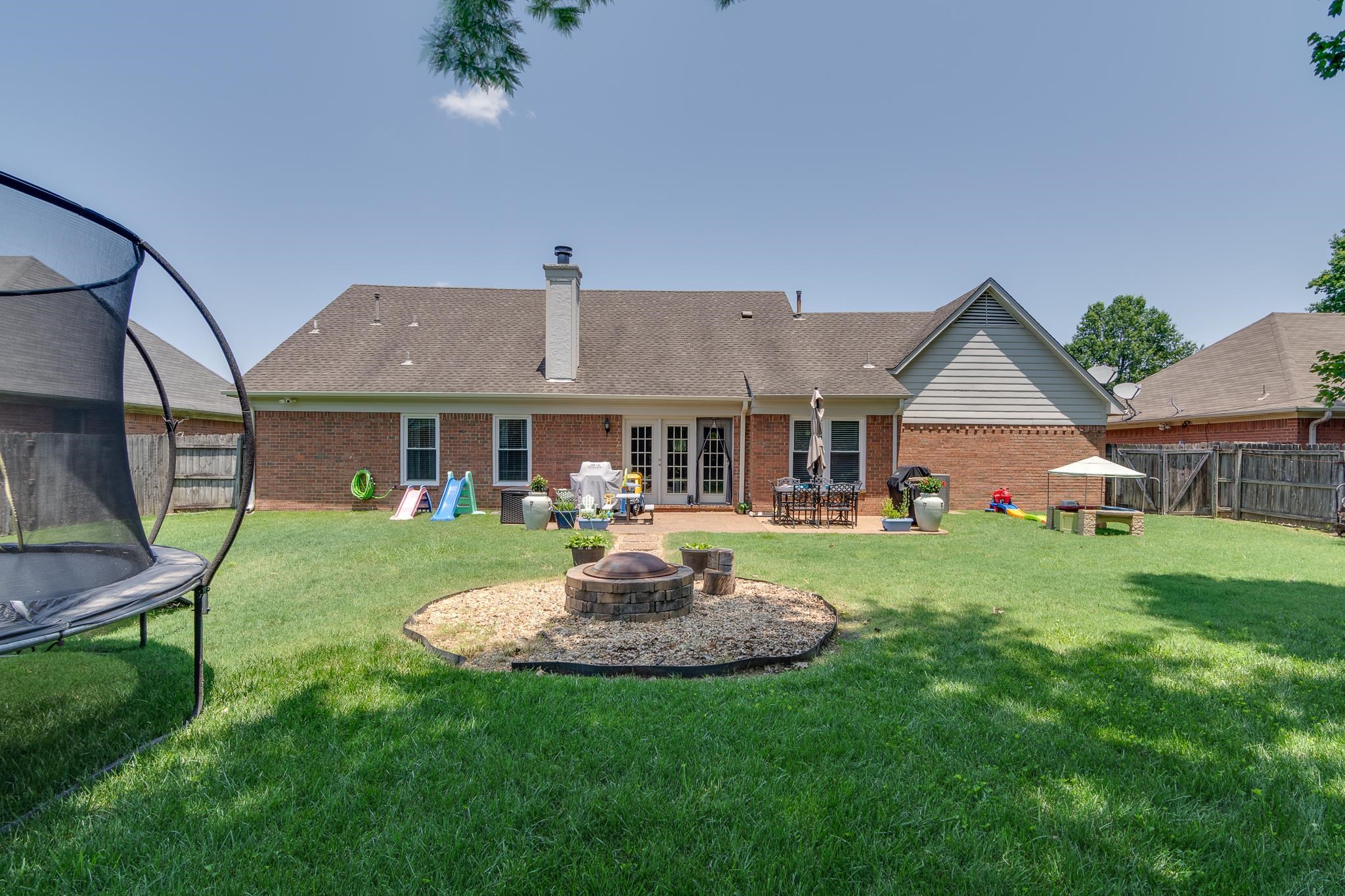 8703 Old River Road Memphis, TN 38018 - Photo 26 of 31 Rear view of property with a trampoline, a fire pit, brick siding, a patio, and a fenced backyard